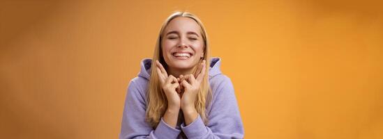 encantador por sorte fofa jovem feliz esperançoso loiro menina fechar olhos sorridente positivo Cruz dedos Boa sorte quer ganhar fielmente Rezar faço desejo desejo Sonhe venha verdadeiro, em pé laranja fundo foto