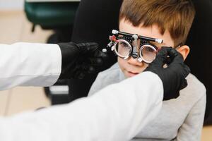 alegre criança Garoto dentro óculos Verificações olho visão pediatra oftalmologista foto