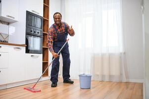 profissional limpador dentro azul uniforme lavando chão e limpando poeira a partir de a mobília dentro a vivo quarto do a apartamento. limpeza serviço conceito foto