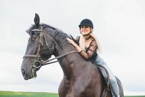 jovem mulher equitação uma cavalo em a verde campo foto