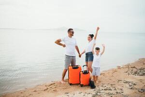 jovem família e filho com bagagem em tropical branco de praia foto