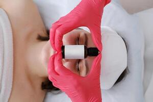 cosmetologista aplicando sérum em do cliente face foto