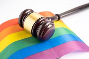 martelo para advogado juiz na bandeira do arco-íris, símbolo do mês do orgulho LGBT, comemora anualmente em junho social de gays, lésbicas, bissexuais, transgêneros, direitos humanos. foto