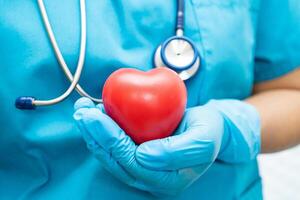 médico segurando um coração vermelho na enfermaria do hospital, conceito médico forte e saudável. foto