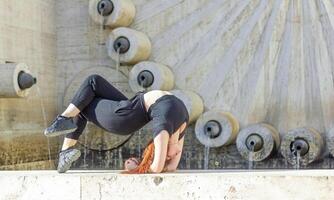 jovem menina fazendo exercício dentro a cidade, mulher fazendo ioga exercício, pessoa fazendo alongamento, mulher relaxante dentro a cidade, bonita menina fazendo ginástica exercício foto