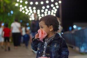 a pequeno Garoto come doces dentro a noite foto