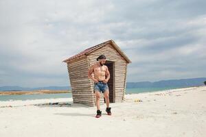 jovem muscular homem exercício em a praia, jovem muscular homem fazendo musculação exercícios em a praia, Atlético jovem homem em a de praia foto