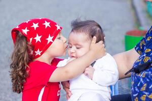 a pequeno Garoto dentro a parque é se beijando dele recém-nascido irmão foto