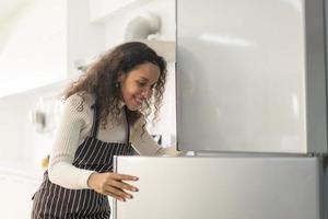 mulher latina com geladeira ou geladeira aberta foto
