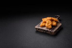 deliciosos nuggets de frango crocantes frescos em um fundo escuro de concreto foto