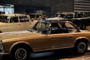 estugarda, alemanha - 16 de outubro de 2018 museu mercedes. carros retrô estacionados na sala de exposição. pessoa com chapéu fica atrás foto