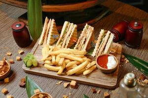 de madeira corte borda com metade sanduíche e francês fritas foto