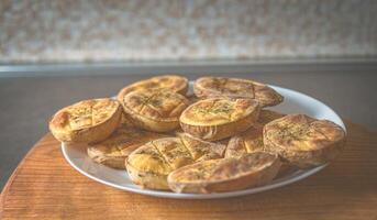 cozido batatas dentro a forno dentro uma branco prato em uma de madeira borda foto