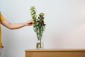 mulher mão organizar colorida flores ramalhete dentro pedreiro jarra em mesa fundo. feliz dia com fresco flor foto