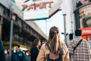 turista mulher Visita ameyoko mercado, uma ocupado mercado rua localizado dentro ueno. ponto de referência e popular para turista atração e viagem destino dentro Tóquio, Japão e Ásia conceito foto