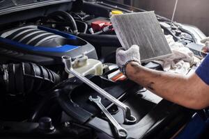 carro ar condicionador sistema manutenção, mão mecânico segurando carro ar filtro para Verifica para limpar \ limpo sujo ou consertar reparar calor ter uma problema ou substituir Novo ou mudança filtro. foto