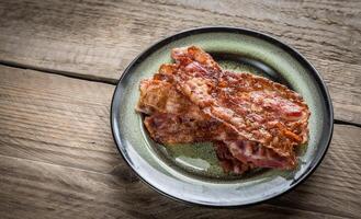 pilha do frito bacon tiras em a prato foto