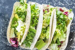 quatro vegetariano tacos em uma Preto fundo foto