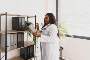 medicamento, pessoas e cuidados de saúde conceito - africano americano fêmea médico ou enfermeira às hospital. foto