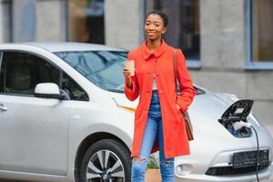 perguntando sobre Novo tecnologia. mulher em a elétrico carros carregar estação às dia. foto