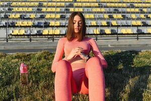 mulher de aptidão fazendo abdominais no estádio malhando. garota esportiva fazendo exercícios abdominais, ao ar livre foto