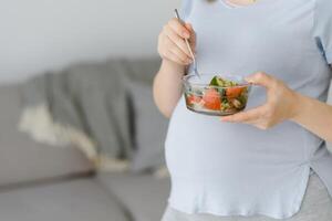 lindo saudável grávida mulher comendo vegetal salada foto