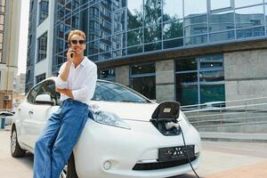 bonito homem usando telefone enquanto carro ser carregada foto