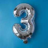 3 três metálico balão isolado em azul fundo. cumprimento cartão prata frustrar balão número feliz aniversário feriado conceito. cópia de espaço para texto. celebração festa parabéns decoração foto