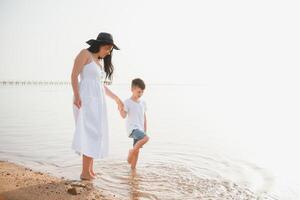 mãe e filho caminhando em pôr do sol de praia foto