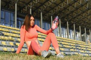 jovem sorridente fêmea em repouso depois de a ativo ginástica treinamento. foto