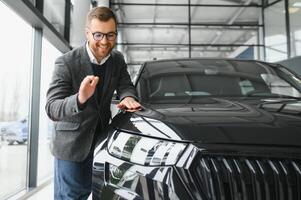 visitando carro concessionária. bonito barbudo homem é acariciando dele Novo carro e sorridente foto