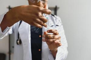 cuidados de saúde e médico conceito - africano médico segurando seringa com injeção. foto