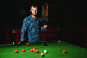 jovem jogando bilhar no clube de bilhar escuro foto