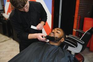 jovem afro-americano homem visitando barbearia foto