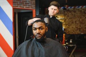 jovem afro-americano homem visitando barbearia foto