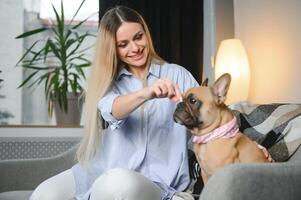 jovem bonita mulher dentro casual roupas abraçando dela cachorro sentado em a sofá dentro a vivo quarto do dela acolhedor país casa. animal comunicação conceito foto