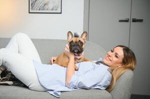 pessoas com animais de estimação conceito. sorridente mulher jogando em sofá com cachorro às casa foto