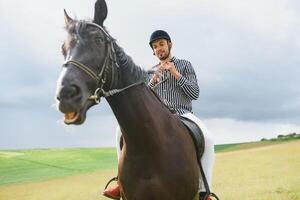 lindo homem equitação uma cavalo em campo às verão foto