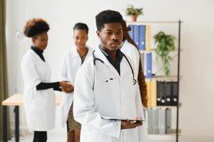 retrato do uma africano médico dentro frente do dele médico equipe. foto