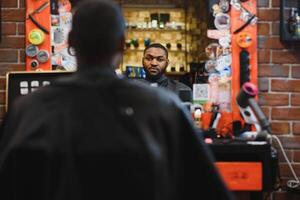 jovem afro-americano homem visitando barbearia foto