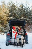 fofa casal tendo inverno floresta piquenique bebendo chá a partir de chá levar longe copo. natureza piquenique. amor história encontro às carro. foto