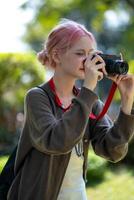 lindo jovem artista mulher levando foto dentro flores jardim. jovem fofa menina levar a Câmera dentro a jardim