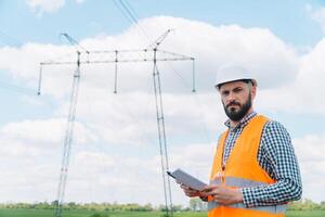 engenheiro trabalhando perto transmissão linhas. eletricidade postes foto