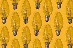 amarelo fundo. elétrico luz lâmpadas padronizar. a velho vidro elétrico luz lâmpada com uma tungstênio filamento. a conceito do eletricidade consumo e economizando. foto