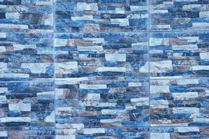pedra parede fez do cinzento e azul tijolos, decorativo azulejos. padronizar elemento do a externo fachada. foto