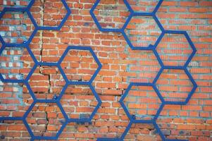 decorativo ferro padronizar do Preto metal dentro a forma do uma favo de mel em a fundo do uma vermelho tijolo muro. foto