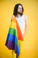 gay homem aguarde arco Iris listrado bandeira isolado em colori fundo estúdio retrato. pessoas estilo de vida moda lgbtq conceito foto