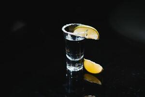 tequila com Lima em uma Sombrio fundo foto