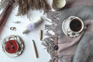 atmosférico plano deitar em a branco de madeira escrivaninha com de lã xadrez, copo do café, bolo, decoração, vela. hygge estilo. foto