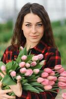 lindo jovem sorridente garota, trabalhador com flores dentro estufa. conceito trabalhos dentro a estufa, flores foto